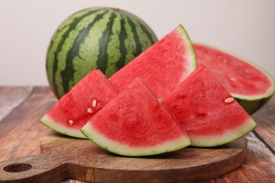 Juicy ripe cut and whole watermelons on wooden table, closeup