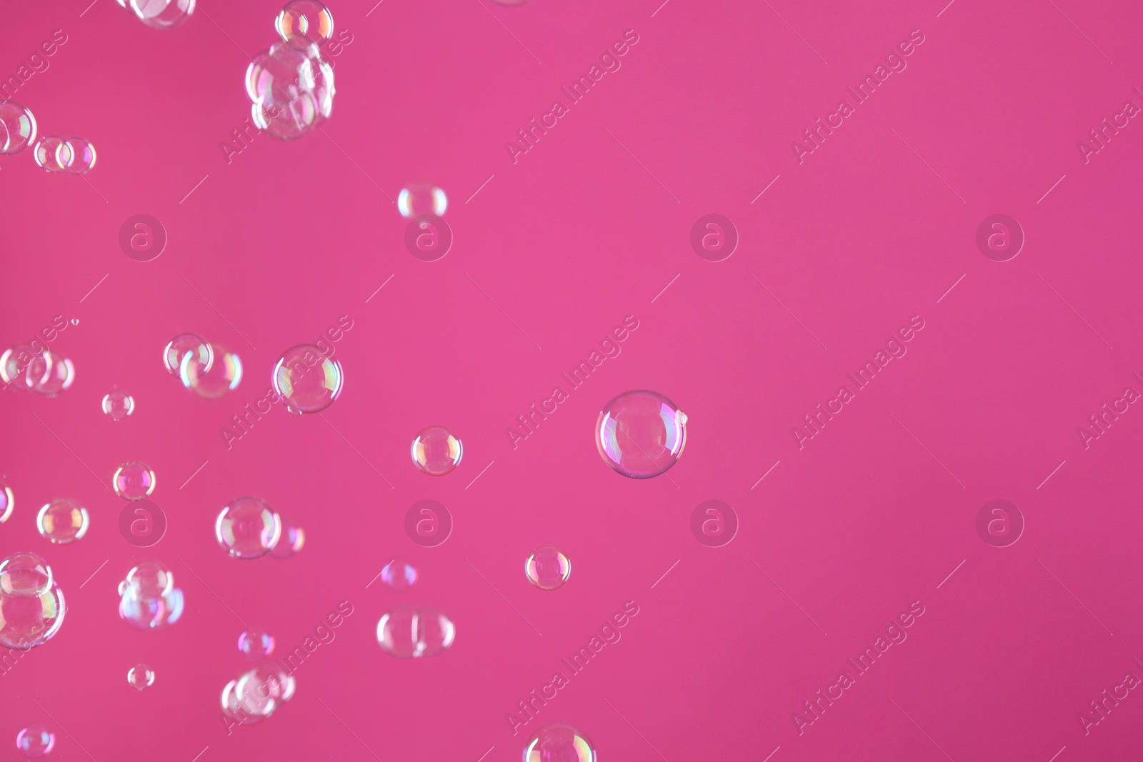 Photo of Beautiful transparent soap bubbles on pink background, space for text