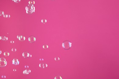 Beautiful transparent soap bubbles on pink background, space for text