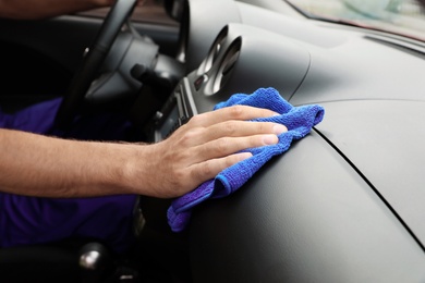 Photo of Man cleaning automobile dashboard with duster, closeup. Car wash service