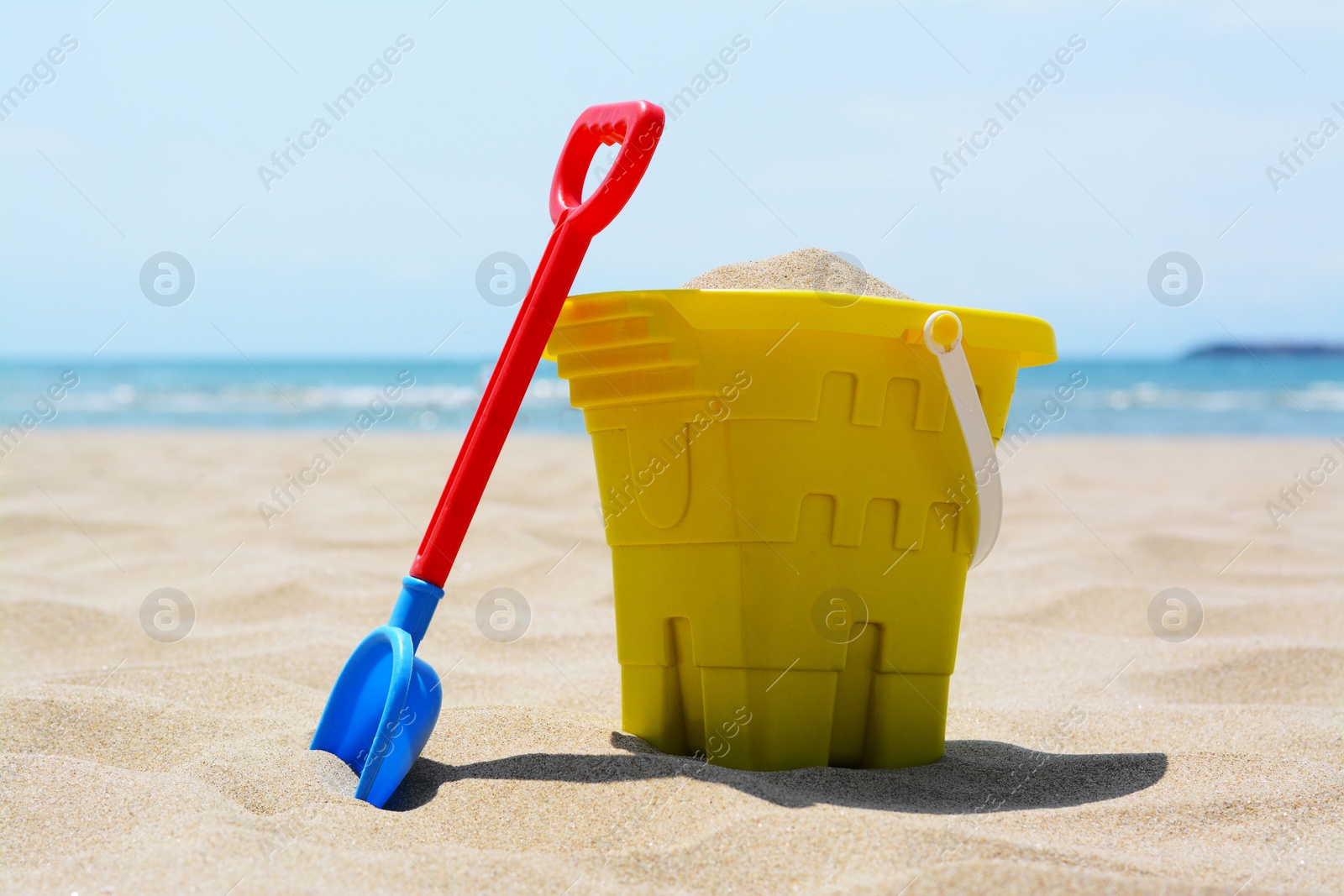 Photo of Plastic bucket and shovel on sand. Beach toys