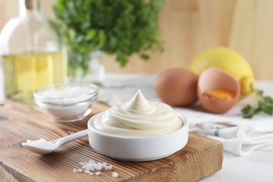 Photo of Fresh mayonnaise sauce in bowl and salt on table