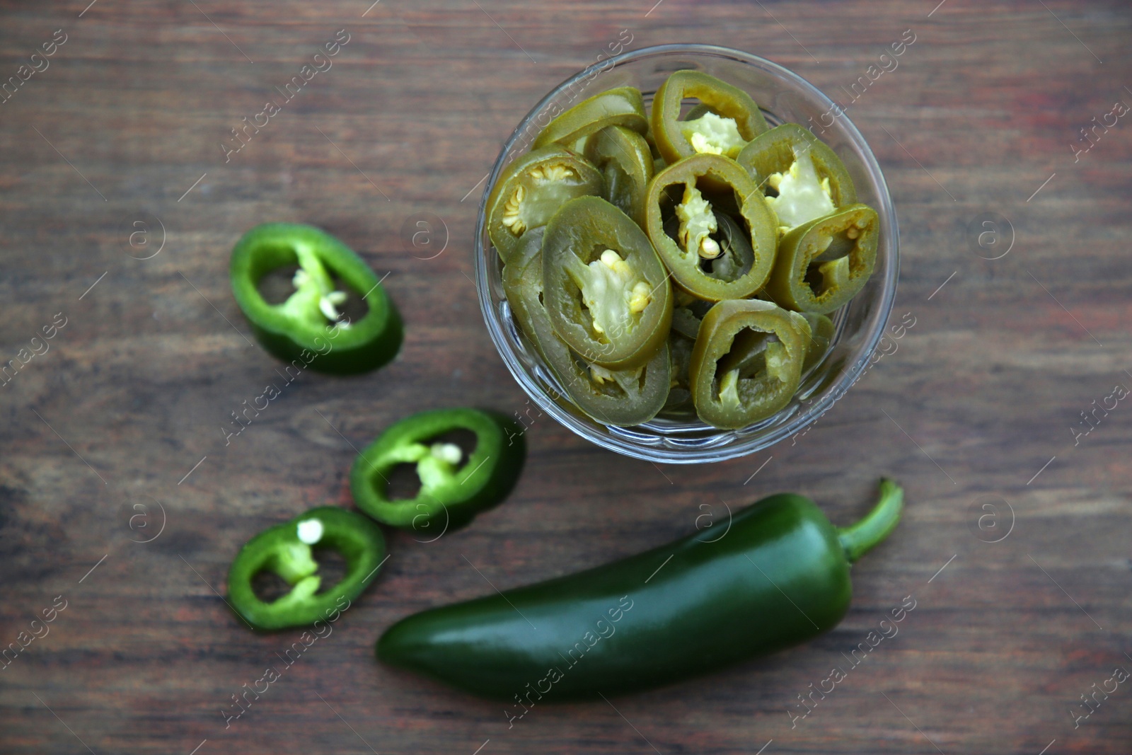 Photo of Fresh and pickled green jalapeno peppers on wooden table, flat lay