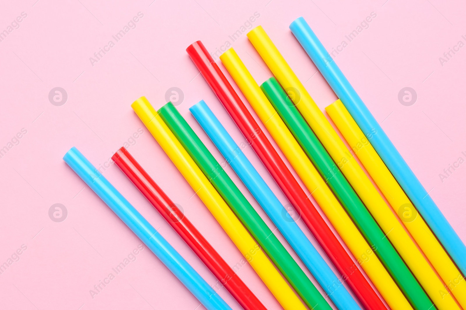 Photo of Many colorful glue sticks on pink background, flat lay