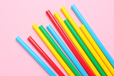 Many colorful glue sticks on pink background, flat lay
