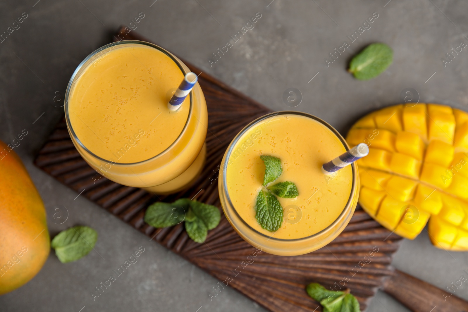 Photo of Glasses of fresh mango drink and fruits on table, top view