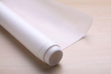 Photo of Roll of baking paper on wooden table, closeup