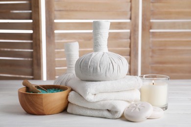 Spa composition with skin care products and burning candle on white wooden table