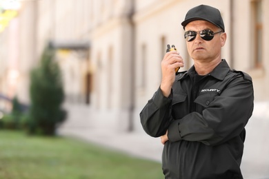 Male security guard using portable radio transmitter outdoors