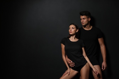 Image of Young couple wearing underwear on black background, space for text