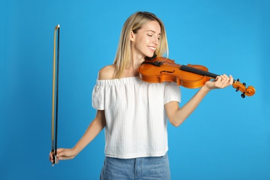 Beautiful woman with violin on blue background