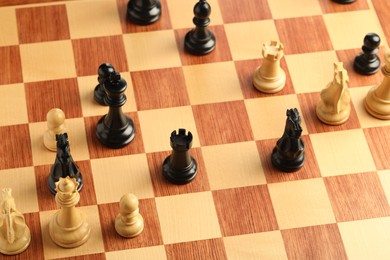 Photo of Wooden chessboard with game pieces, above view
