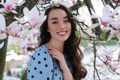 Beautiful woman near blossoming magnolia tree on spring day