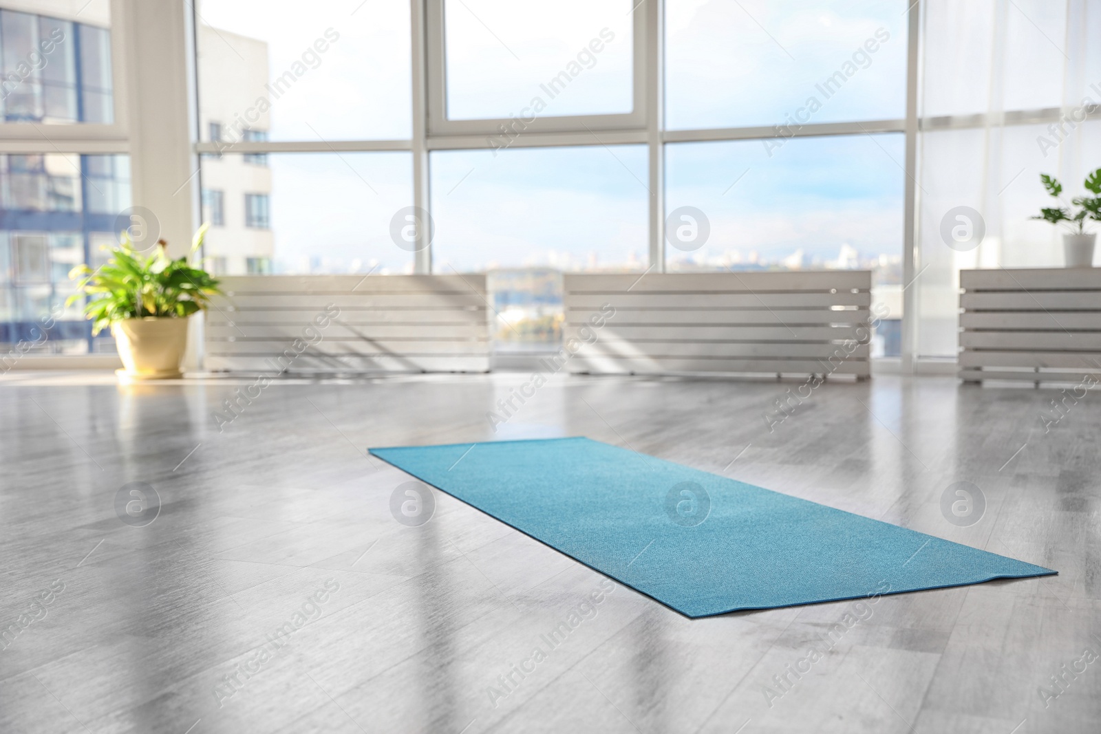 Photo of Unrolled light blue yoga mat on floor in room