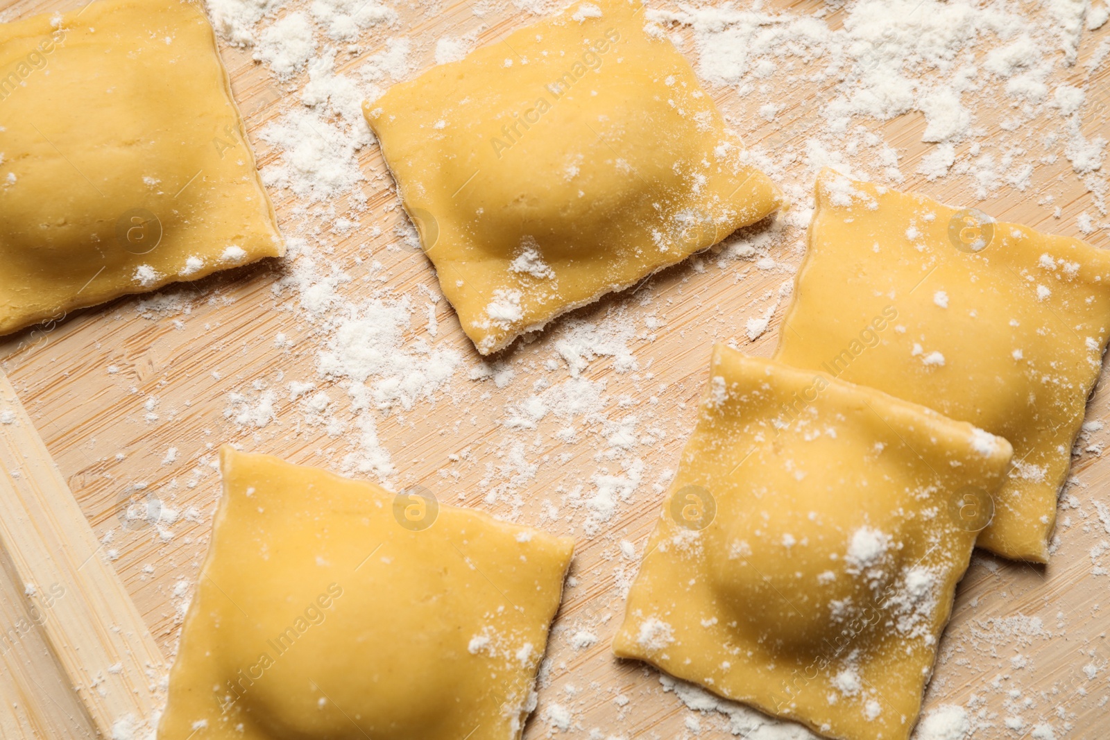 Photo of Raw ravioli on wooden board, closeup view. Italian pasta