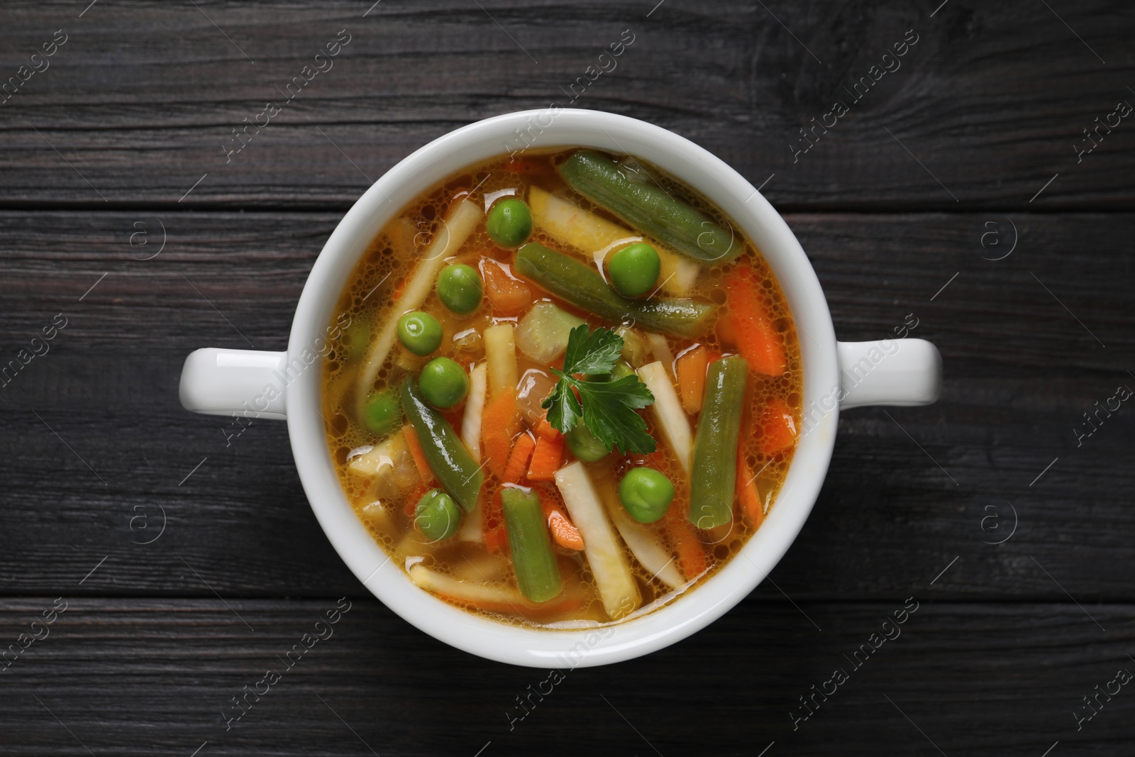 Photo of Bowl of tasty turnip soup on dark wooden table, top view