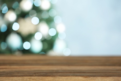 Photo of Empty wooden table and blurred fir tree with Christmas lights on background, bokeh effect. Space for design