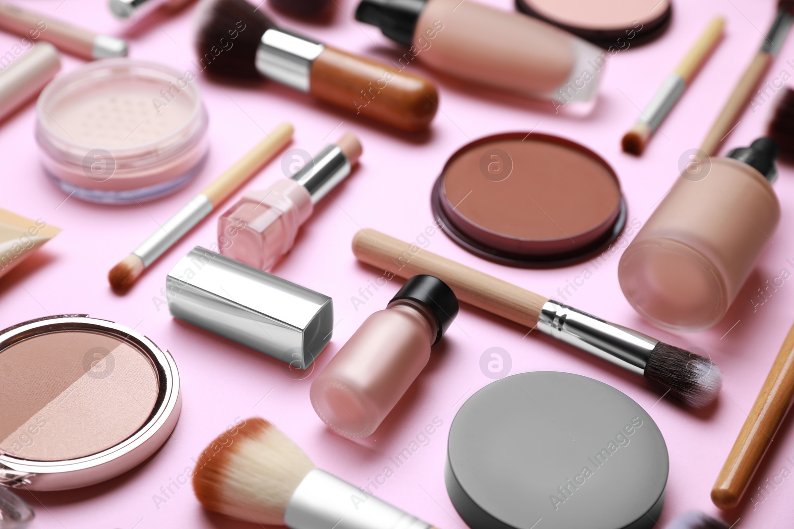 Photo of Face powders and other decorative cosmetic products on pink background