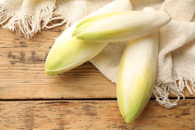 Photo of Fresh raw Belgian endives (chicory) on wooden table, top view