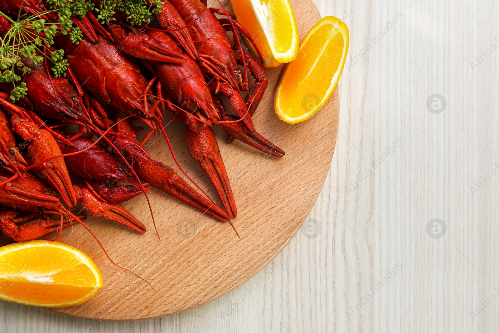 Photo of Delicious red boiled crayfish and orange on white wooden table, top view