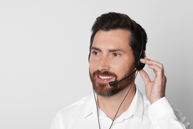 Photo of Hotline operator with headset on light grey background, space for text