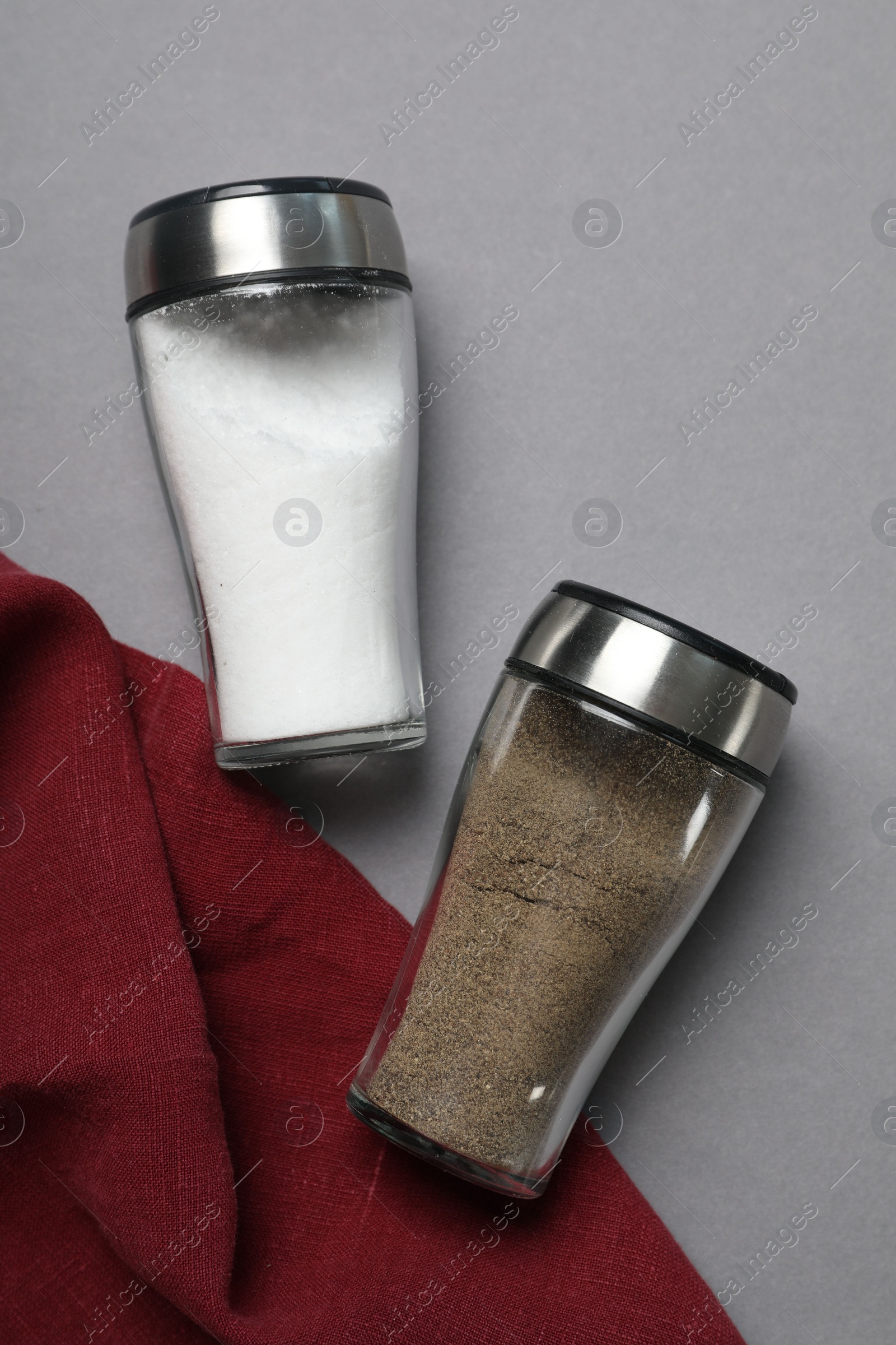 Photo of Salt and pepper shakers on grey table, flat lay