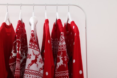 Rack with different Christmas sweaters on white background