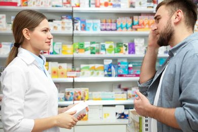 Image of Professional pharmacist working with customer in modern drugstore