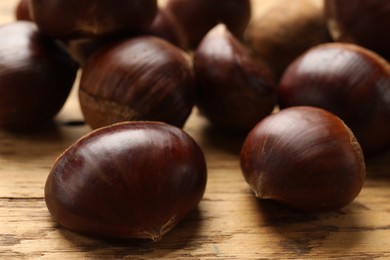 Sweet fresh edible chestnuts on wooden table, closeup