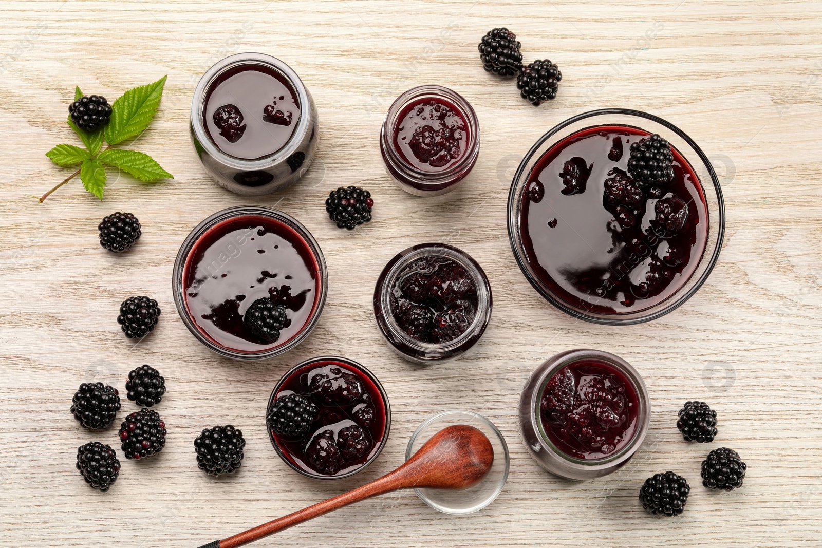 Photo of Tasty blackberry jam and fresh berries on white wooden table, flat lay