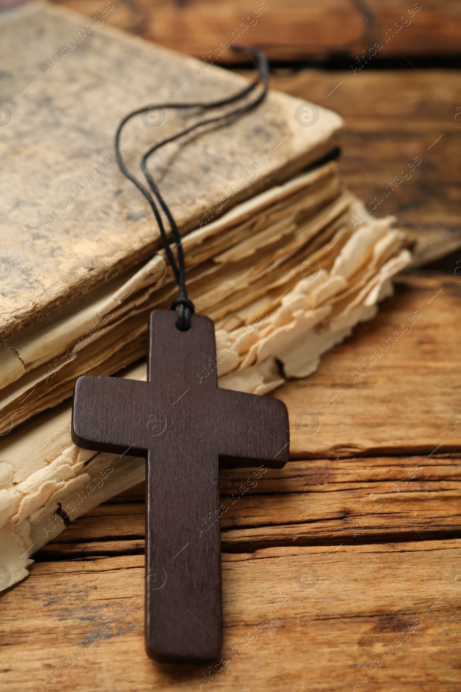 Photo of Christian cross and Bible on wooden table, closeup