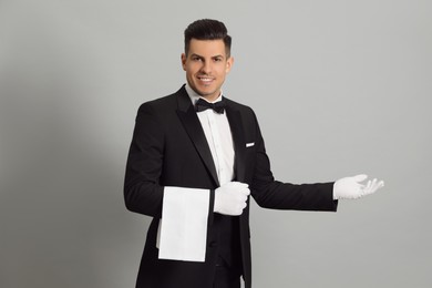 Photo of Handsome butler with towel on grey background