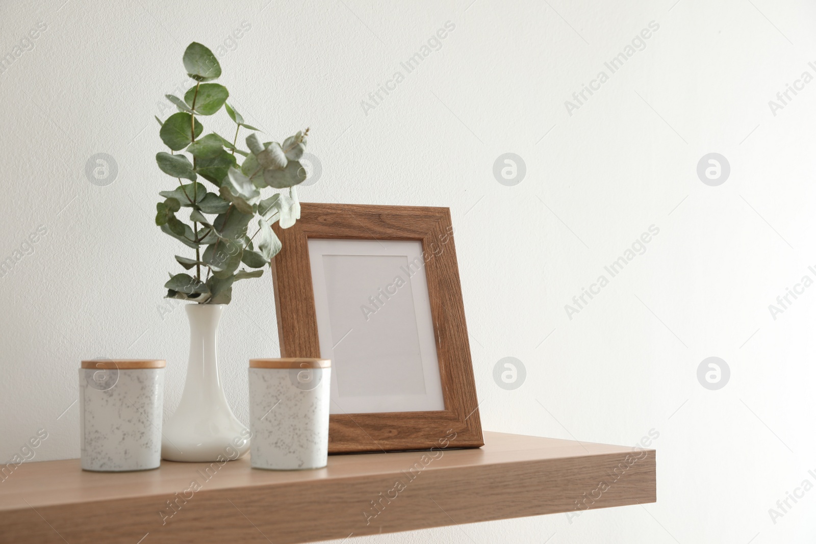 Photo of Wooden shelf with photo frame and decorative elements on light wall