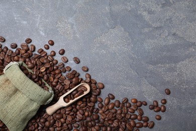 Photo of Roasted coffee beans, bag and wooden scoop on grey table, flat lay. Space for text