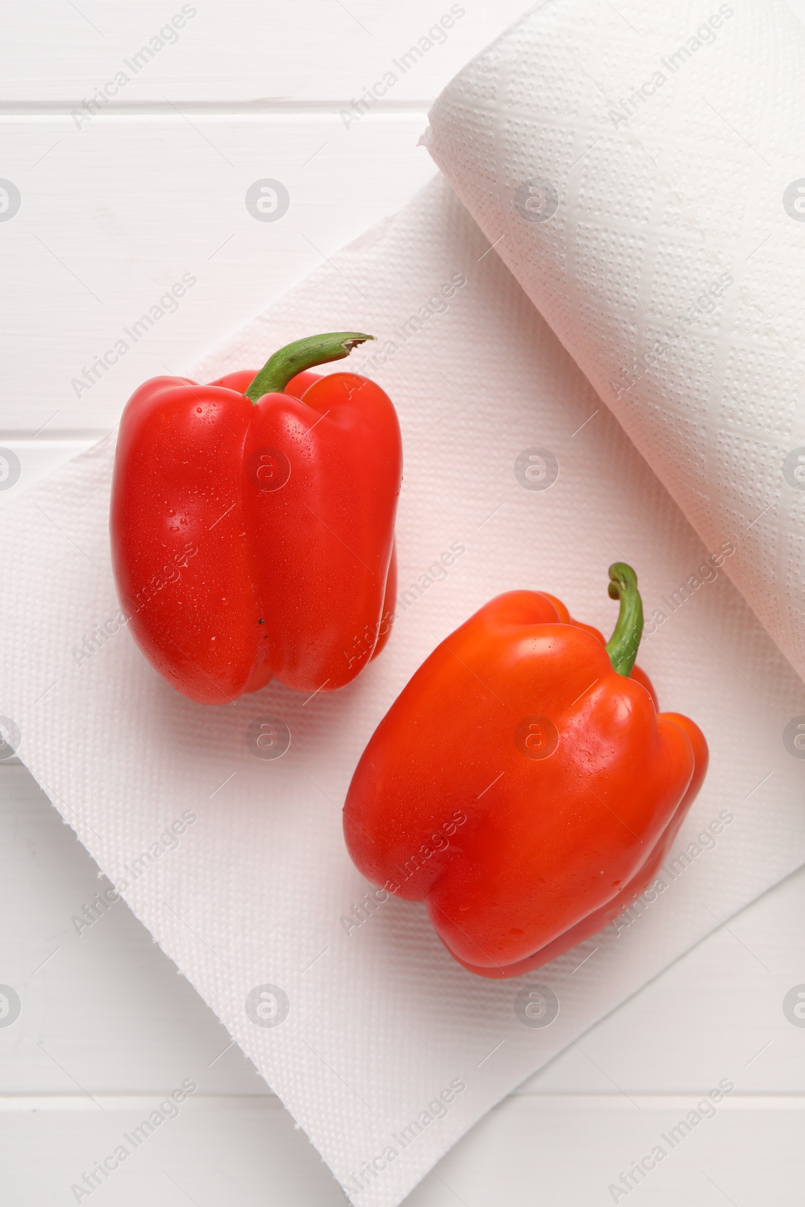 Photo of Roll of paper towels with bell peppers on white wooden table, top view