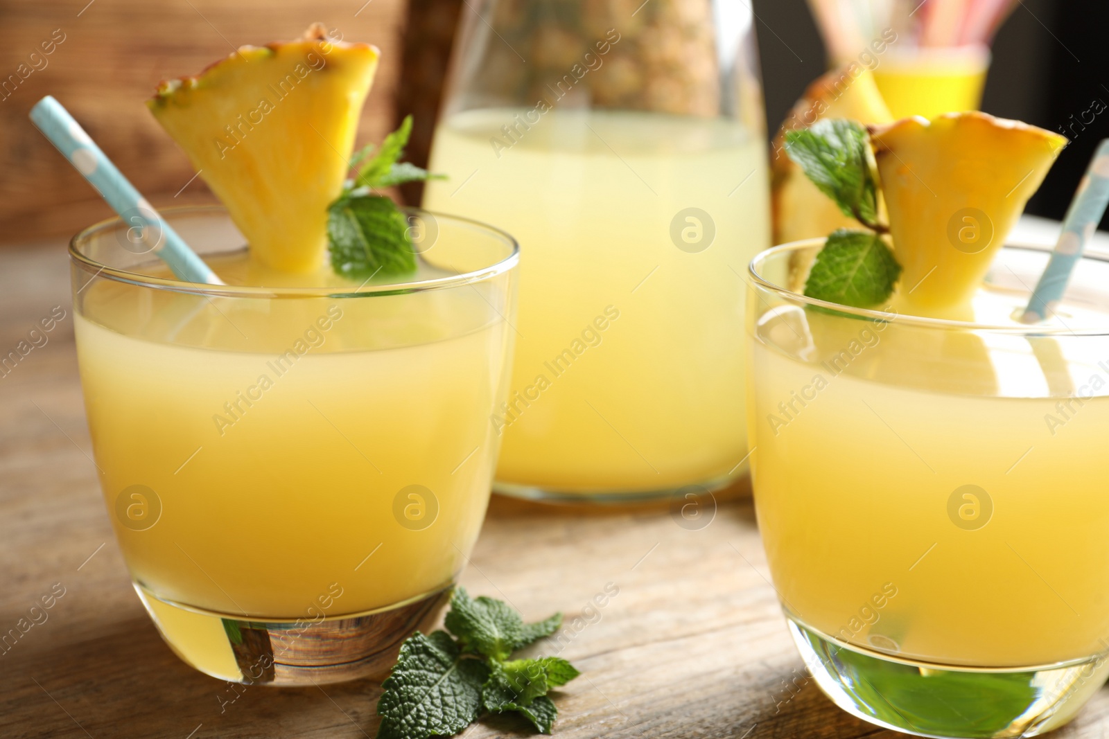 Photo of Delicious fresh pineapple juice with mint on wooden table, closeup