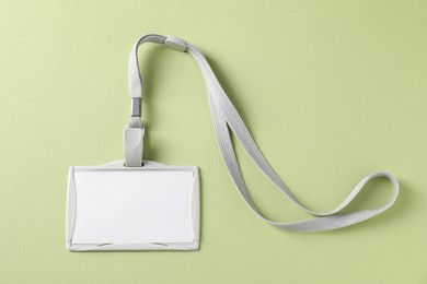 Photo of Blank badge with string on light green background, top view