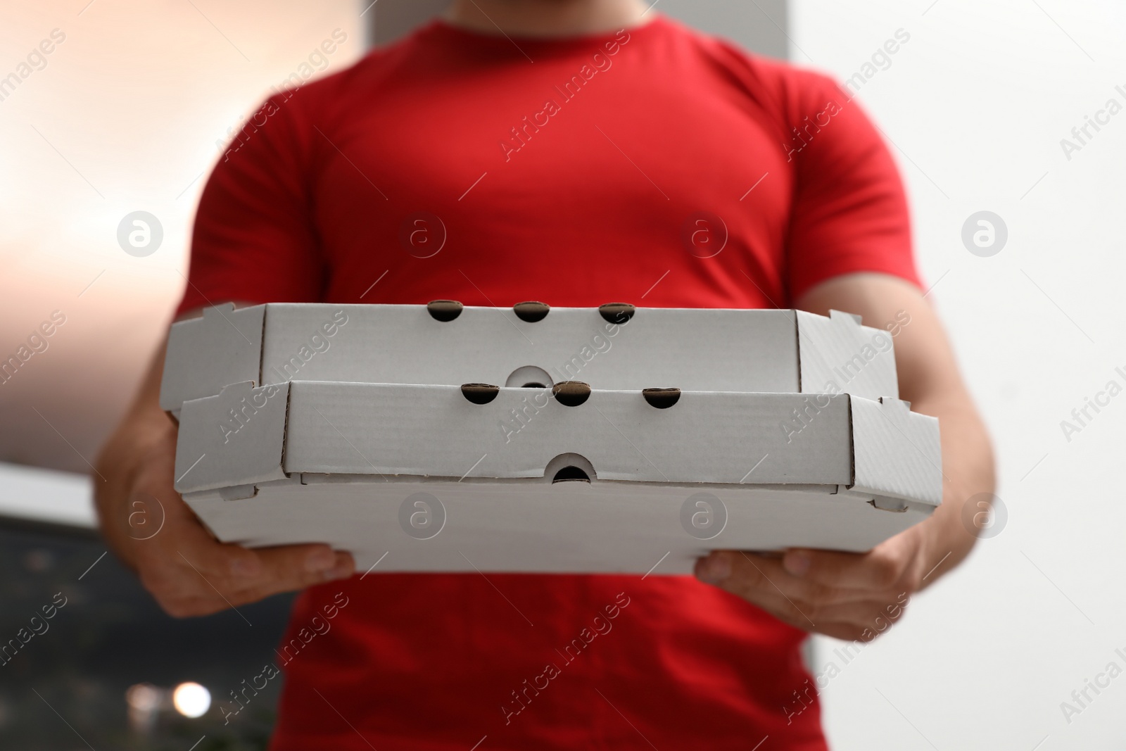 Photo of Courier with pizza boxes on blurred background, closeup