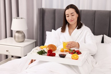 Young woman having breakfast in bed at home, space for text