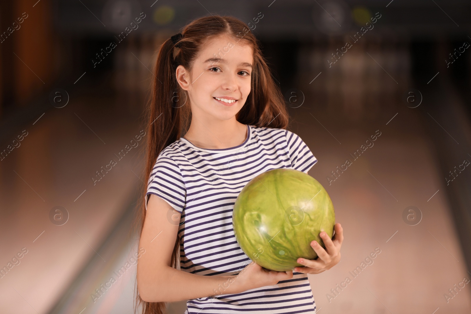 Photo of Preteen girl with ball in bowling club