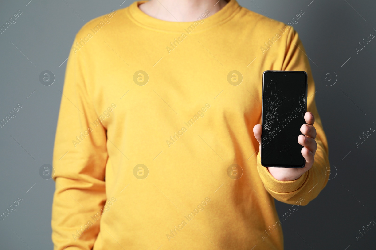 Photo of Man showing damaged smartphone on light grey background, closeup. Device repairing