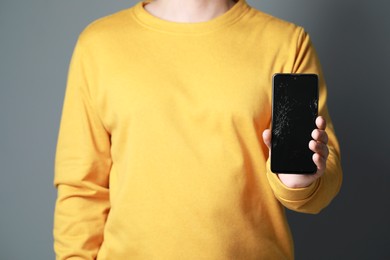 Photo of Man showing damaged smartphone on light grey background, closeup. Device repairing