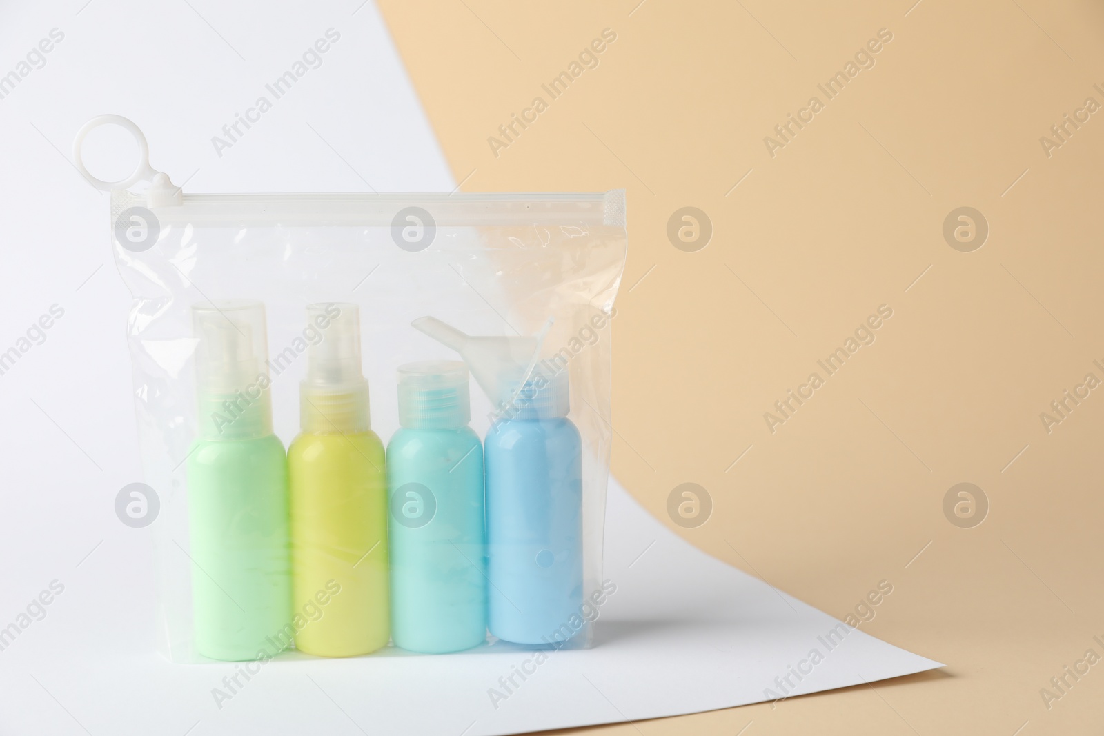 Photo of Cosmetic travel kit in plastic bag on color background, space for text. Bath accessories