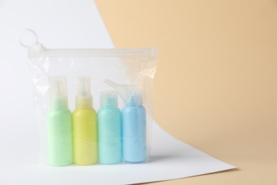 Cosmetic travel kit in plastic bag on color background, space for text. Bath accessories