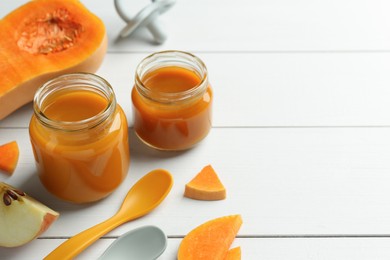 Photo of Tasty baby food in jars and ingredients on white wooden table, closeup. Space for text