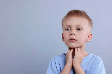 Photo of Endocrine system. Little boy doing thyroid self examination on light grey background, space for text