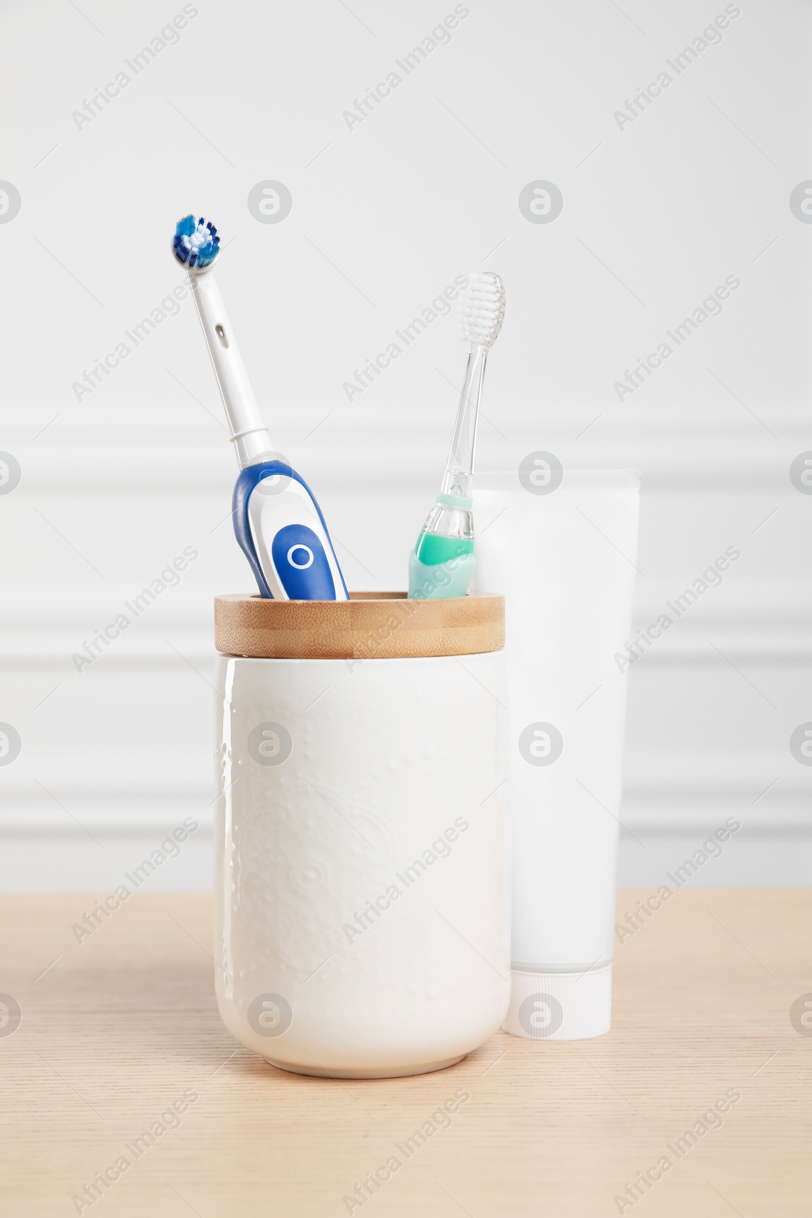 Photo of Electric toothbrushes and tube of paste on wooden table