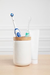 Electric toothbrushes and tube of paste on wooden table