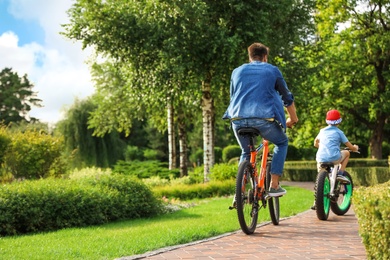 Photo of Dad and son riding modern bicycles outdoors