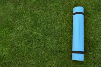 Bright karemat or fitness mat on fresh green grass outdoors, top view. Space for text